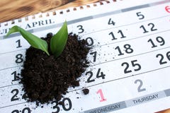 Op de lijst is een kalenderblad met een kleine stapel van aarde met een installatiespruit stock afbeelding Op de lijst is een kalenderblad met een kleine stapel van aarde met een installatiespruit stock afbeelding