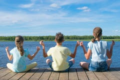 In the open air, on the pier, near the water, children are engaged in relaxation in the form of yoga stock images In the open air, on the pier, near the water, children are engaged in relaxation in the form of yoga stock images