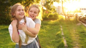 Openlucht Portret De tienermeisjes koesteren en lachen op een achtergrond van zonlicht, gelukkige kinderjaren, schoolvakantie stock videobeelden Openlucht Portret De tienermeisjes koesteren en lachen op een achtergrond van zonlicht, gelukkige kinderjaren, schoolvakantie stock videobeelden