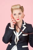 Operador fêmea louro com bordos vermelhos que chama sobre o telefone de orador vermelho do receptor A mulher atrativa com ondas l fotografia de stock royalty free Operador fêmea louro com bordos vermelhos que chama sobre o telefone de orador vermelho do receptor A mulher atrativa com ondas l fotografia de stock royalty free
