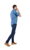 Opini?o traseira o homem que anda com um telefone celular fotografia de stock Opini?o traseira o homem que anda com um telefone celular fotografia de stock