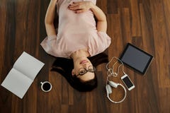 A opinião superior uma menina positiva com sorrisos dos vidros encontra-se no floo fotografia de stock A opinião superior uma menina positiva com sorrisos dos vidros encontra-se no floo fotografia de stock