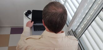 Opinião traseira um homem que veste a camisa oficial do colar que senta-se perto da janela fotografia de stock royalty free Opinião traseira um homem que veste a camisa oficial do colar que senta-se perto da janela fotografia de stock royalty free