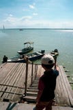 Opinión los niños que miran un lazo del hombre una cuerda para asegurar su barco a un embarcadero de madera imagenes de archivo Opinión los niños que miran un lazo del hombre una cuerda para asegurar su barco a un embarcadero de madera imagenes de archivo