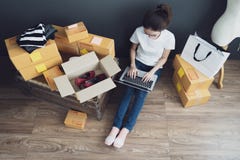 Opinión superior las mujeres que trabajan el ordenador portátil del hogar en piso de madera con el paquete postal, vendiendo conc fotografía de archivo Opinión superior las mujeres que trabajan el ordenador portátil del hogar en piso de madera con el paquete postal, vendiendo conc fotografía de archivo