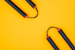 Opleidingsnunchaku op een gele achtergrond wordt geïsoleerd die E stock fotografie Opleidingsnunchaku op een gele achtergrond wordt geïsoleerd die E stock fotografie
