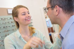 Optician показывая стекла для того чтобы укомплектовать личным составом в магазине оптики стоковые изображения Optician показывая стекла для того чтобы укомплектовать личным составом в магазине оптики стоковые изображения