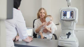 Optometrist checks child`s eyesight - mother and child in ophthalmologist room stock photo Optometrist checks child`s eyesight - mother and child in ophthalmologist room stock photo