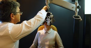Optometrist die geduldige ogen met messbrille 4k onderzoeken stock footage Optometrist die geduldige ogen met messbrille 4k onderzoeken stock footage