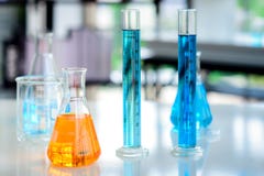 Orange Chemikalien in der Flasche und blaue Chemikalien in den Zylinderrohren auf dem Tisch gesetzt lizenzfreies stockbild Orange Chemikalien in der Flasche und blaue Chemikalien in den Zylinderrohren auf dem Tisch gesetzt lizenzfreies stockbild