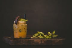 Orange cocktail with a mint leaf on a wooden tray