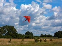 Orange drake på molnig himmel- och fältbakgrunden Royaltyfri Bild Orange drake på molnig himmel- och fältbakgrunden Royaltyfri Bild