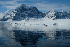 Orange Kajak der Antarktis in einer blauen Bucht des Spiegels unter Schnee bedeckte Berge mit einer Kappe lizenzfreies stockfoto Orange Kajak der Antarktis in einer blauen Bucht des Spiegels unter Schnee bedeckte Berge mit einer Kappe lizenzfreies stockfoto
