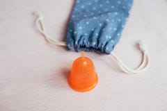 Orange menstruations- kopp nära bomullspåse på rosa bakgrund arkivbilder Orange menstruations- kopp nära bomullspåse på rosa bakgrund arkivbilder