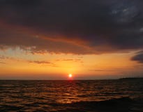Orange solnedgång för ljus sommar under en mörk åskmoln i havet arkivfoton Orange solnedgång för ljus sommar under en mörk åskmoln i havet arkivfoton