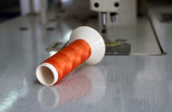 Orange thread in the thread roll put horizontal on the sewing machine. Royalty Free Stock Photos Orange thread in the thread roll put horizontal on the sewing machine. Royalty Free Stock Photos