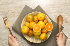 Oranje mand en handholdingslepel en vork En een mooie houten achtergrond stock afbeeldingen Oranje mand en handholdingslepel en vork En een mooie houten achtergrond stock afbeeldingen
