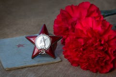Orden de Red Star con el St, dos claveles rojos y y mentira del libro de los soldier’s en una lona Primer imagen de archivo libre de regalías Orden de Red Star con el St, dos claveles rojos y y mentira del libro de los soldier’s en una lona Primer imagen de archivo libre de regalías