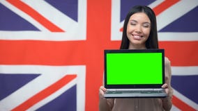 Ordinateur portable de représentation femelle avec l'écran vert sur le fond britannique de drapeau, étude banque de vidéos Ordinateur portable de représentation femelle avec l'écran vert sur le fond britannique de drapeau, étude banque de vidéos