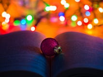 Ornement rouge de Noël de scintillement sur un livre ouvert avec des lumières de Noël à l'arrière-plan photographie stock Ornement rouge de Noël de scintillement sur un livre ouvert avec des lumières de Noël à l'arrière-plan photographie stock