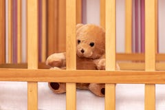 Orsacchiotto del giocattolo in una culla di bambino immagini stock Orsacchiotto del giocattolo in una culla di bambino immagini stock
