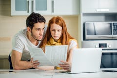 Orçamento de controlo da família, revendo suas contas bancárias usando o portátil na cozinha foto de stock Orçamento de controlo da família, revendo suas contas bancárias usando o portátil na cozinha foto de stock