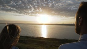 Os amantes admiram o por do sol, caminhada no banco de rio vídeos de arquivo Os amantes admiram o por do sol, caminhada no banco de rio vídeos de arquivo