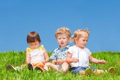 Os bebês sentam-se na grama fotografia de stock Os bebês sentam-se na grama fotografia de stock