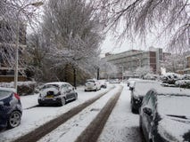 Os carros cobertos de neve estacionados na árvore nevado alinharam a rua urbana suburbana da cidade durante tempestades da neve e fotos de stock Os carros cobertos de neve estacionados na árvore nevado alinharam a rua urbana suburbana da cidade durante tempestades da neve e fotos de stock