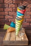 Os chifres coloridos para o gelado em um frasco estão em uma caixa de madeira em um teste padrão de contraste da sombra das corti fotografia de stock Os chifres coloridos para o gelado em um frasco estão em uma caixa de madeira em um teste padrão de contraste da sombra das corti fotografia de stock