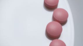 Os comprimidos cor-de-rosa estão movendo sobre um fundo branco video estoque Os comprimidos cor-de-rosa estão movendo sobre um fundo branco video estoque