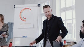 Os executivos multi-étnicos escutam o homem envelhecido médio do treinador que explica vendas no escritório moderno, EPOPEIA VERM video estoque Os executivos multi-étnicos escutam o homem envelhecido médio do treinador que explica vendas no escritório moderno, EPOPEIA VERM video estoque