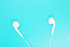 Os fones de ouvido brancos fecham-se acima em um fundo de turquesa, fones de ouvido para escutar a música, dispositivos modernos, foto de stock royalty free Os fones de ouvido brancos fecham-se acima em um fundo de turquesa, fones de ouvido para escutar a música, dispositivos modernos, foto de stock royalty free