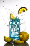 Os limões que caem em um vidro da água de gelo azul com espirram contra isolado no fundo branco Bebida de refrescamento foto de stock Os limões que caem em um vidro da água de gelo azul com espirram contra isolado no fundo branco Bebida de refrescamento foto de stock