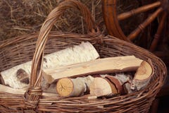 Os logs encontram-se em uma cesta de vime com um punho no fundo dos monte de feno imagem de stock Os logs encontram-se em uma cesta de vime com um punho no fundo dos monte de feno imagem de stock