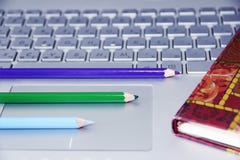 os lápis verdes e roxos azuis encontram-se em um teclado de computador de prata foto de stock os lápis verdes e roxos azuis encontram-se em um teclado de computador de prata foto de stock