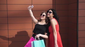 Os melhores amigos fazem o selfie após a compra meninas bonitas nos óculos de sol com os sacos de compras à disposição que tomam video estoque Os melhores amigos fazem o selfie após a compra meninas bonitas nos óculos de sol com os sacos de compras à disposição que tomam video estoque