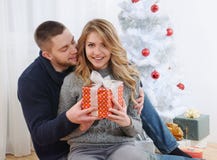 Os pares novos felizes aproximam a árvore de Natal com presente imagens de stock Os pares novos felizes aproximam a árvore de Natal com presente imagens de stock