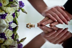 Os recém-casados guardam as mãos ao lado das alianças de casamento que se encontram na superfície do espelho fotografia de stock Os recém-casados guardam as mãos ao lado das alianças de casamento que se encontram na superfície do espelho fotografia de stock