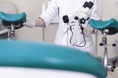 Ottica femminile del microscopio della lente delle mani della stanza del ginecologo della sedia di medico ginecologico dell'attre immagini stock Ottica femminile del microscopio della lente delle mani della stanza del ginecologo della sedia di medico ginecologico dell'attre immagini stock