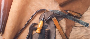 Oud hulpmiddelen en leer op het schoenmakerswerk Het bureau van het schoenmakers` s werk Vlak leg, hoogste mening Reeks hulpmidde stock foto's Oud hulpmiddelen en leer op het schoenmakerswerk Het bureau van het schoenmakers` s werk Vlak leg, hoogste mening Reeks hulpmidde stock foto's