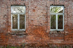 Oude bakstenen muur met oude vensters en de groei royalty-vrije stock afbeelding Oude bakstenen muur met oude vensters en de groei royalty-vrije stock afbeelding