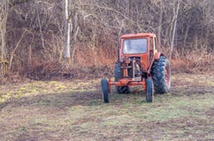 Oude roestige rode antieke tractor van een landbouwbedrijf in het hout stock afbeelding Oude roestige rode antieke tractor van een landbouwbedrijf in het hout stock afbeelding