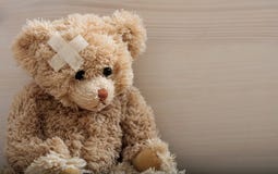 Ours de nounours avec le bandage sur un plancher en bois photographie stock libre de droits Ours de nounours avec le bandage sur un plancher en bois photographie stock libre de droits