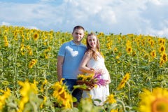 Outdoor portrait of young pregnant couple in sunflowers field on a bright Sunny day. Authentic lifestyle image stock photos Outdoor portrait of young pregnant couple in sunflowers field on a bright Sunny day. Authentic lifestyle image stock photos