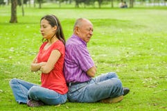 Outdoor view of father and daughter sitting in the grass and back to back each other at outdoors, in the park stock images Outdoor view of father and daughter sitting in the grass and back to back each other at outdoors, in the park stock images