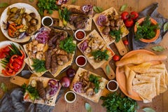 Outdoors концепция еды Аппетитный barbecued стейк, сосиски и зажаренные овощи на деревянном столе для пикника стоковое фото rf Outdoors концепция еды Аппетитный barbecued стейк, сосиски и зажаренные овощи на деревянном столе для пикника стоковое фото rf