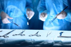 Outils chirurgicaux se trouvant sur la table tandis que groupe de chirurgiens au patient de opération de fond Instruments médicau photos libres de droits Outils chirurgicaux se trouvant sur la table tandis que groupe de chirurgiens au patient de opération de fond Instruments médicau photos libres de droits