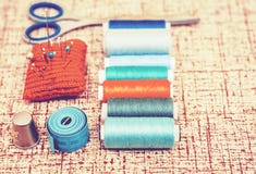 Outils pour la couture, la protection tricot?e rouge d'aiguille pour coudre, les ciseaux et les bobines color?es de fil sur le fo photos libres de droits Outils pour la couture, la protection tricot?e rouge d'aiguille pour coudre, les ciseaux et les bobines color?es de fil sur le fo photos libres de droits