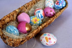 Oval basket full of brightly colored Easter eggs with one white spotted egg beside stock photo Oval basket full of brightly colored Easter eggs with one white spotted egg beside stock photo
